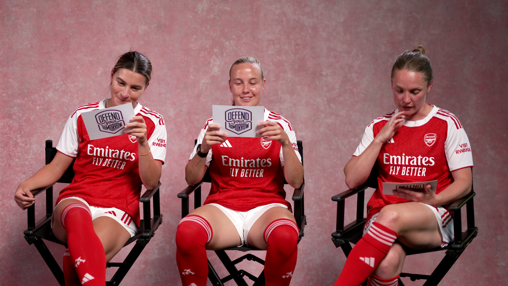 Steph Catley, Beth Mead and Kim Little sit on chairs reading prompt cards.